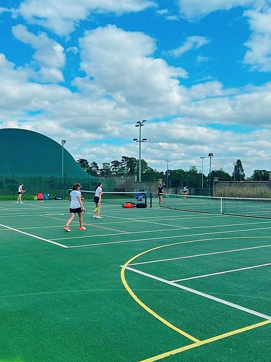 Students playing tennis on the astro turf tennis courts at Culford School