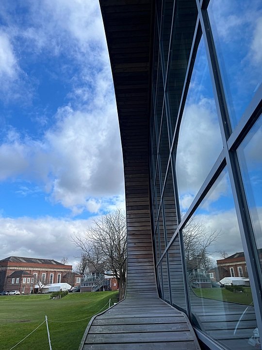 A striking modern school building with curved wooden panels and glass walls.