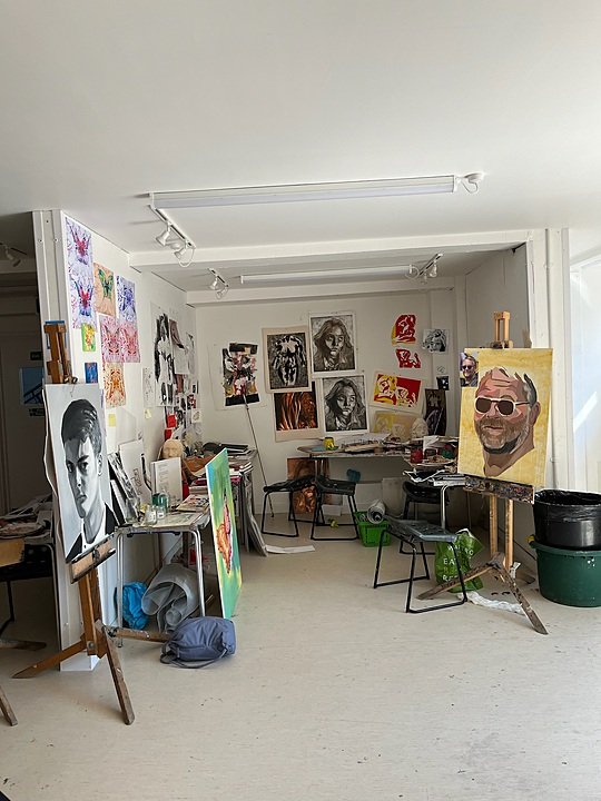 An art classroom filled with paintings, sketches, and easels displaying student artwork.