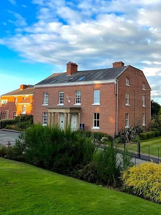 An attractive red-brick house with green lawn in front of it
