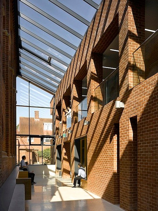Red brick building from the inside with large window ceiling and boys chatting