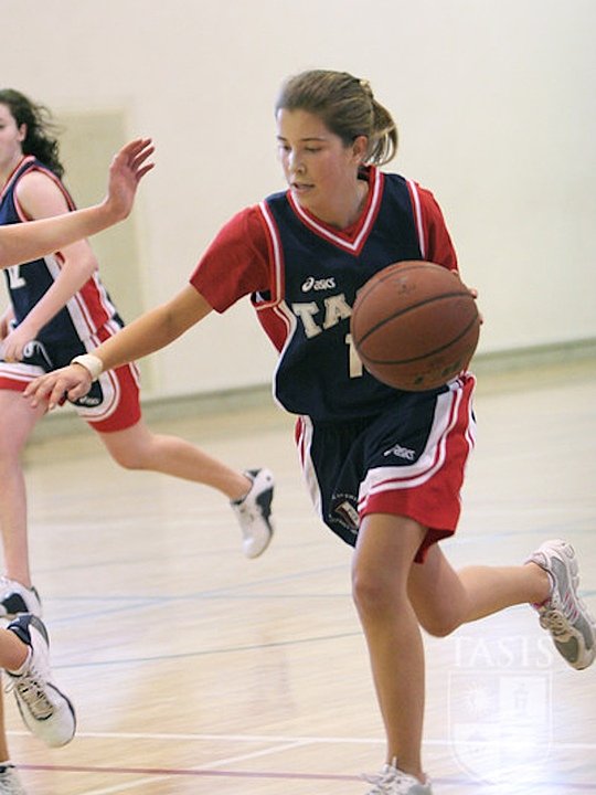 Girl in basketball jersey and basketball mid-run