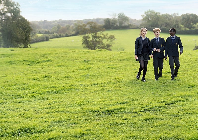 three Sidcot Students in their uniforms on a walk on the green school campus