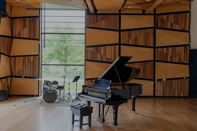 A grand piano and drum set in a beautiful modern wood-paneled audition room