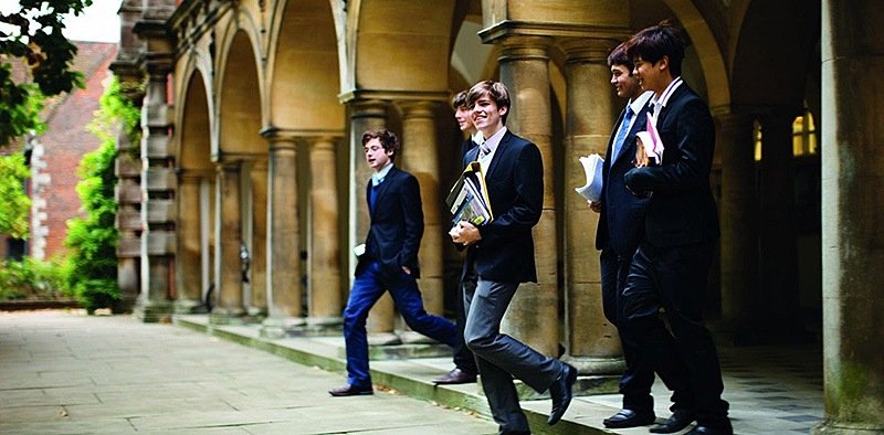 Five boys stepping from a building smiling