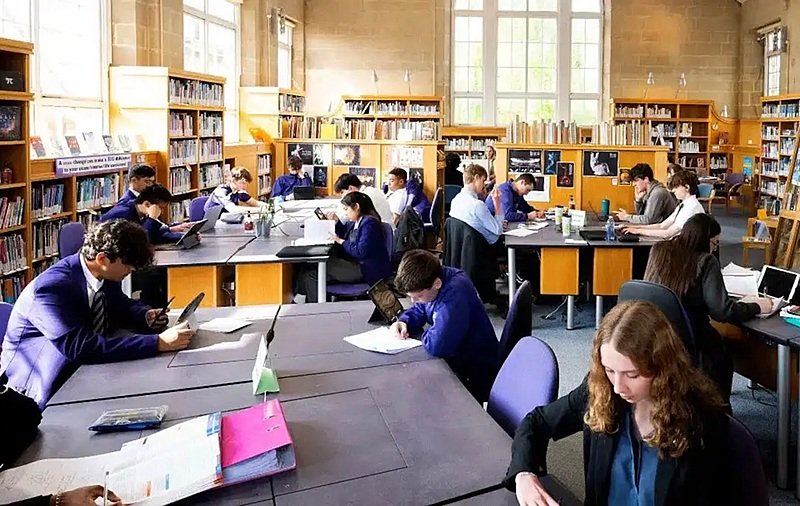 A library with lots of bookshelves and pupils sitting at tables working