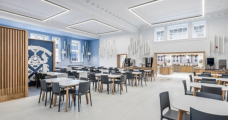 A beautiful, modern, well-lit dining hall with white windows frames and ceilings, tables and chairs