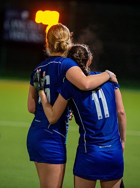 Two girls from the Canford School Hockey team hugging by the pitch