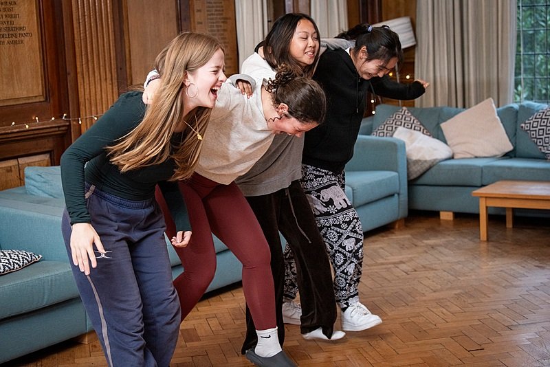 Four female students laughing and having fun in a boarding house at Clifton College