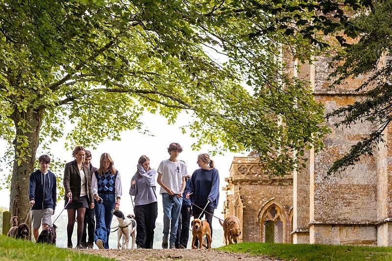 a group of students on a walk over the school campus with several dogs on the leash