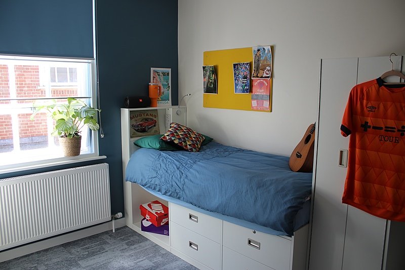 A modern single room with white furniture and a blue wall in a boarding house