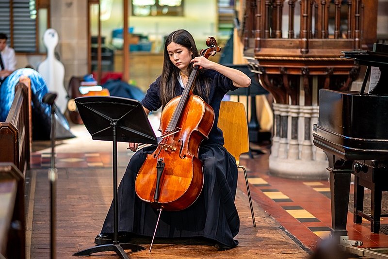 Student playing cello during school concert performance