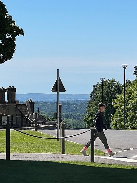 panorama view into the countryside from Worth School with a boy crossing the road in the foreground