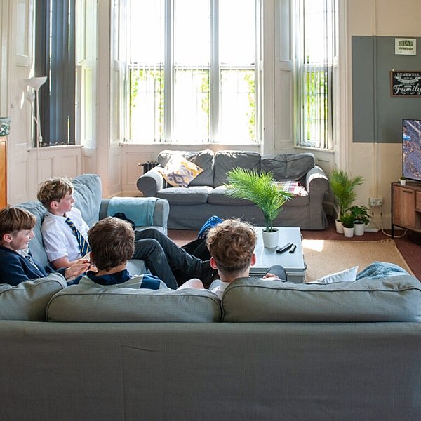 Four boys sitting on a sofa staring at a screen, playing a computer game