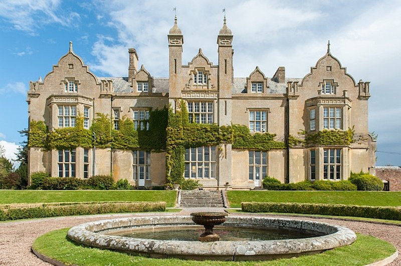 Sand stone building from the Victorian era with pond and fountain in front
