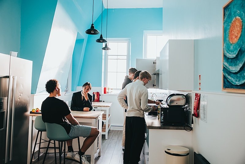 A boarding house kitchen with five boys talking and eating