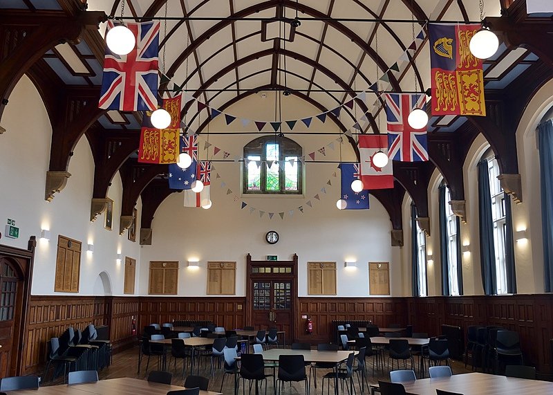 A big dining hall with very high ceiling and wooden beam construction decorated with international flags and buntings