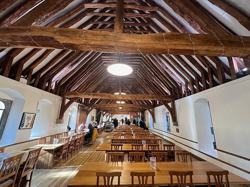 endless rows of tables in the dining hall with a beautiful old wooden beam construction under the ceiling