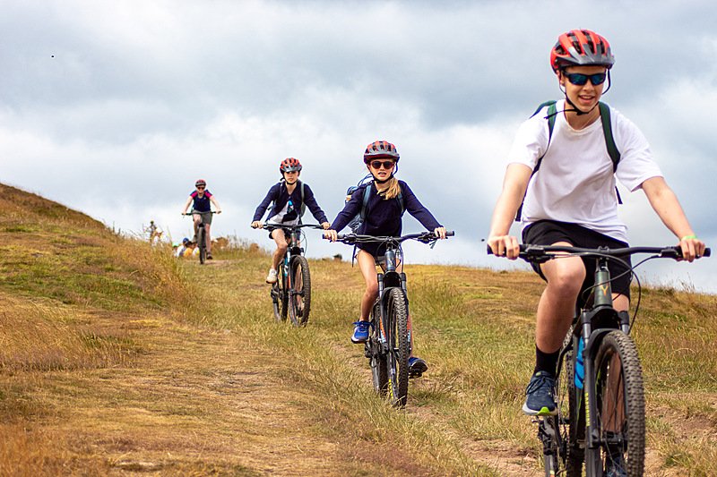 Summer School students going down hill during their Mountain Biking trip