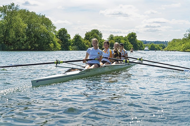 Four girls in a four-seater rowing boat on a river in good weather