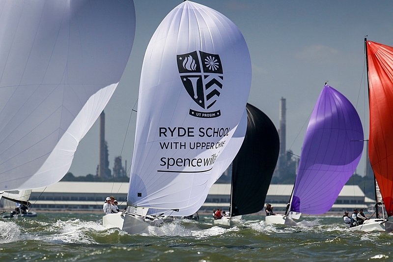 A sailing boat with Ryde School on the sail in a regatta with lots of other competitors