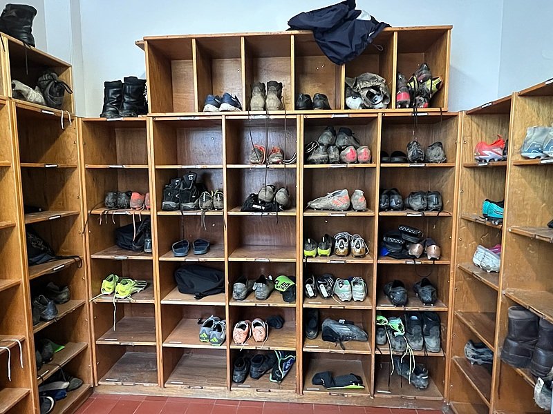 A room with shoe shelves on the walls full of muddy sports shoes