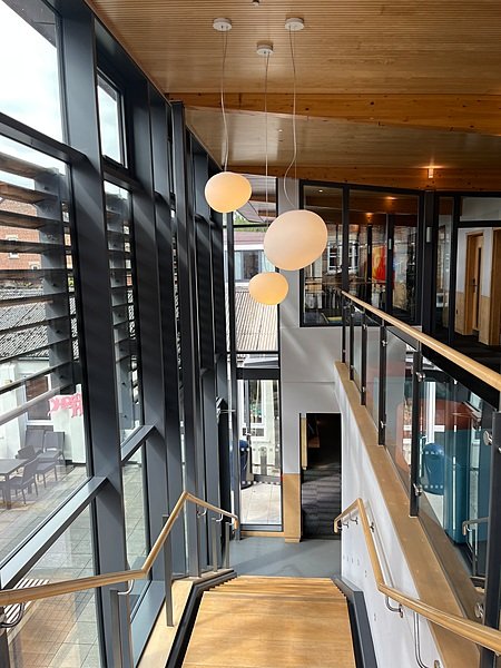 a modern and light flooded staircase with wood, floor to ceiling windows and warm lighting