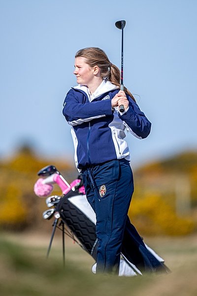 A female student taking a backswing with her golf club on the golf course