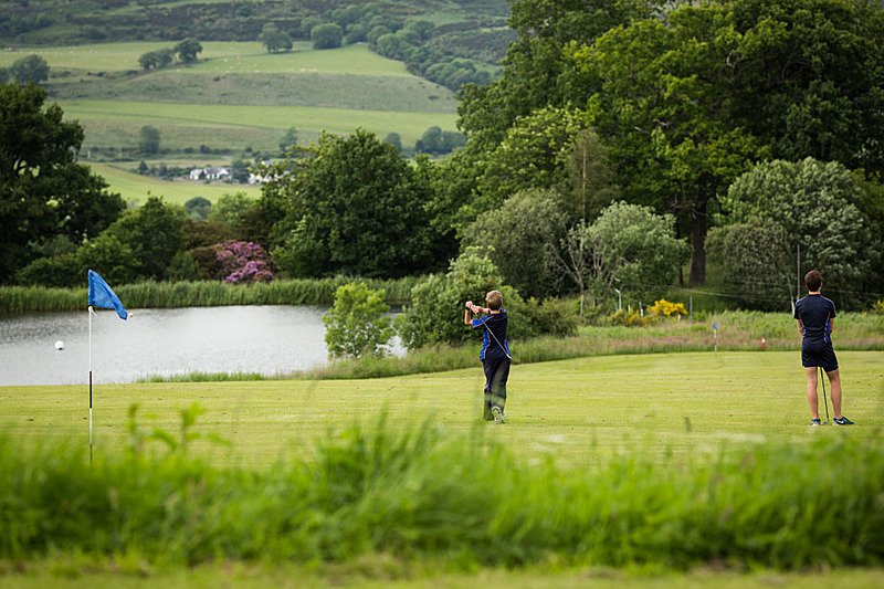Two golf players on a beautiful golf course with a lake behind them