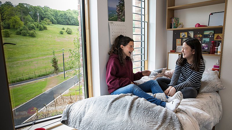 Two girls sitting on a bed, laughing